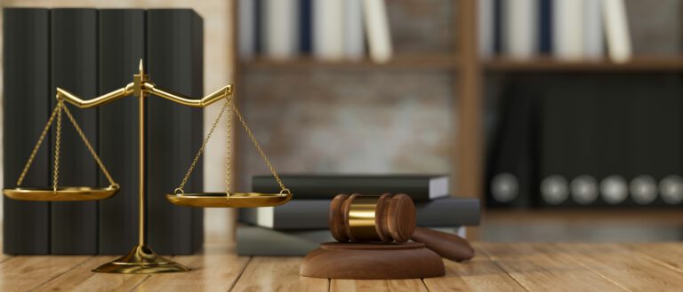 Justitiawaage und Richterhammer, die auf einem Tisch stehen